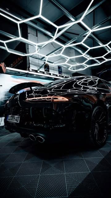 Schwarzer Sportwagen nach Lackpolitur unter LED-Wabenlicht